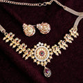 Antique gold floral temple necklace set with ruby and green stones and matching earrings on maroon background